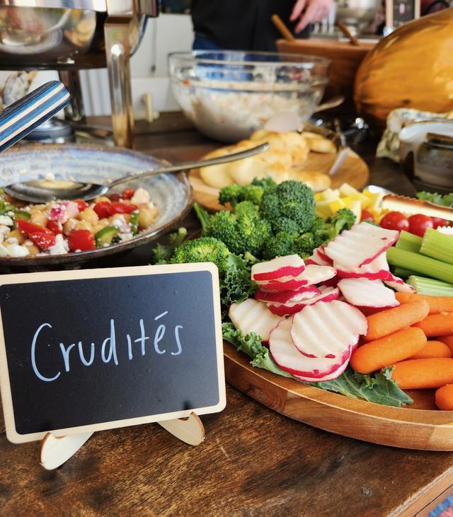 A crudités platter of broccoli, radishes, celery and carrots beside a chalkboard sign