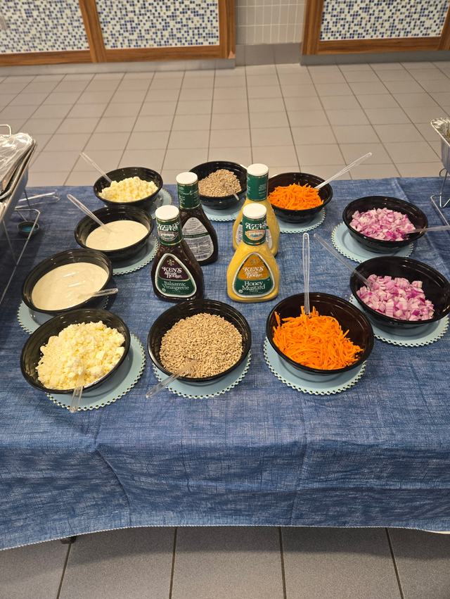 Salad bar toppings with shredded carrots, red onion, sunflower seeds, cheese and dressings