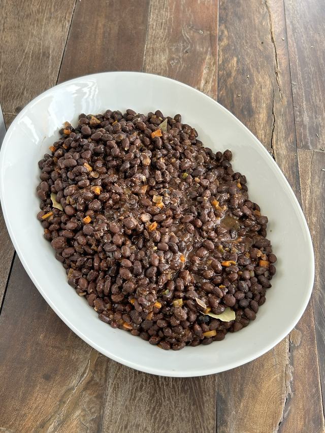 A serving bowl of seasoned black beans with bay leaves